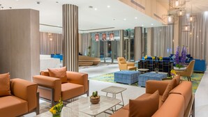 Un hall d’entrée moderne avec des sièges orange, un espace d’accueil et un ensemble de canapés bleus.