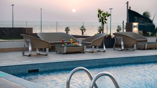Un espace aménagé au bord de la piscine, avec des chaises longues et une vue sur la mer.