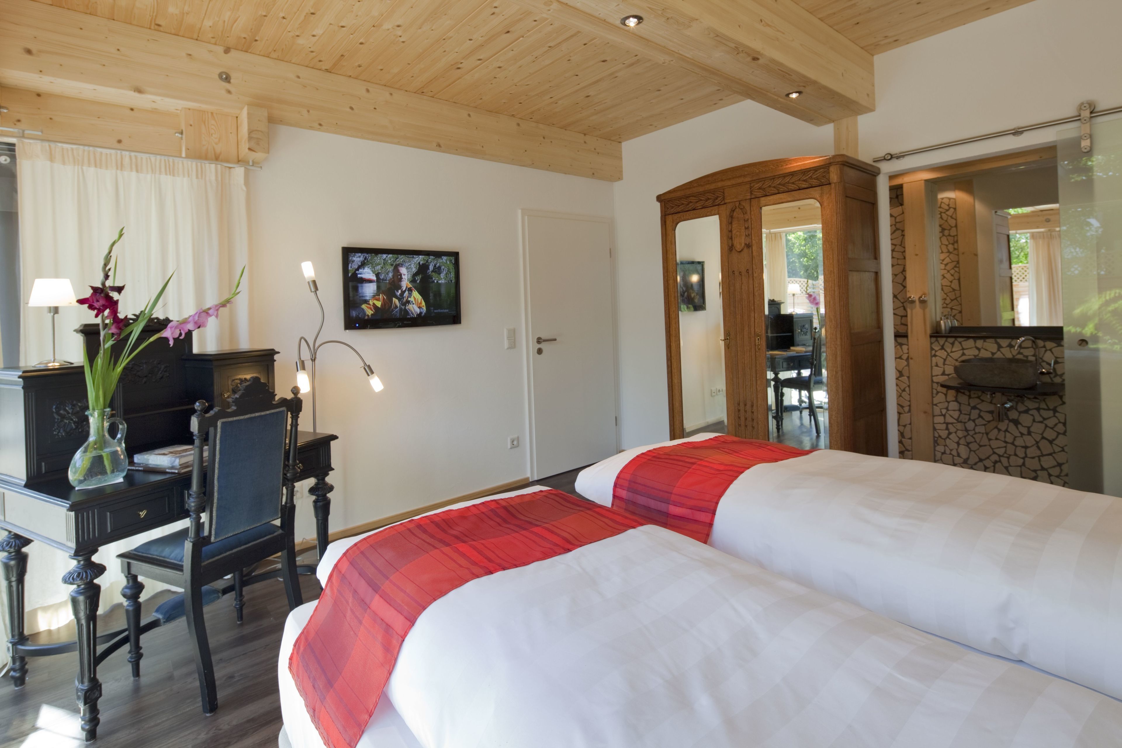 Habitación de hotel con dos camas, un escritorio con silla, televisión y espejo.