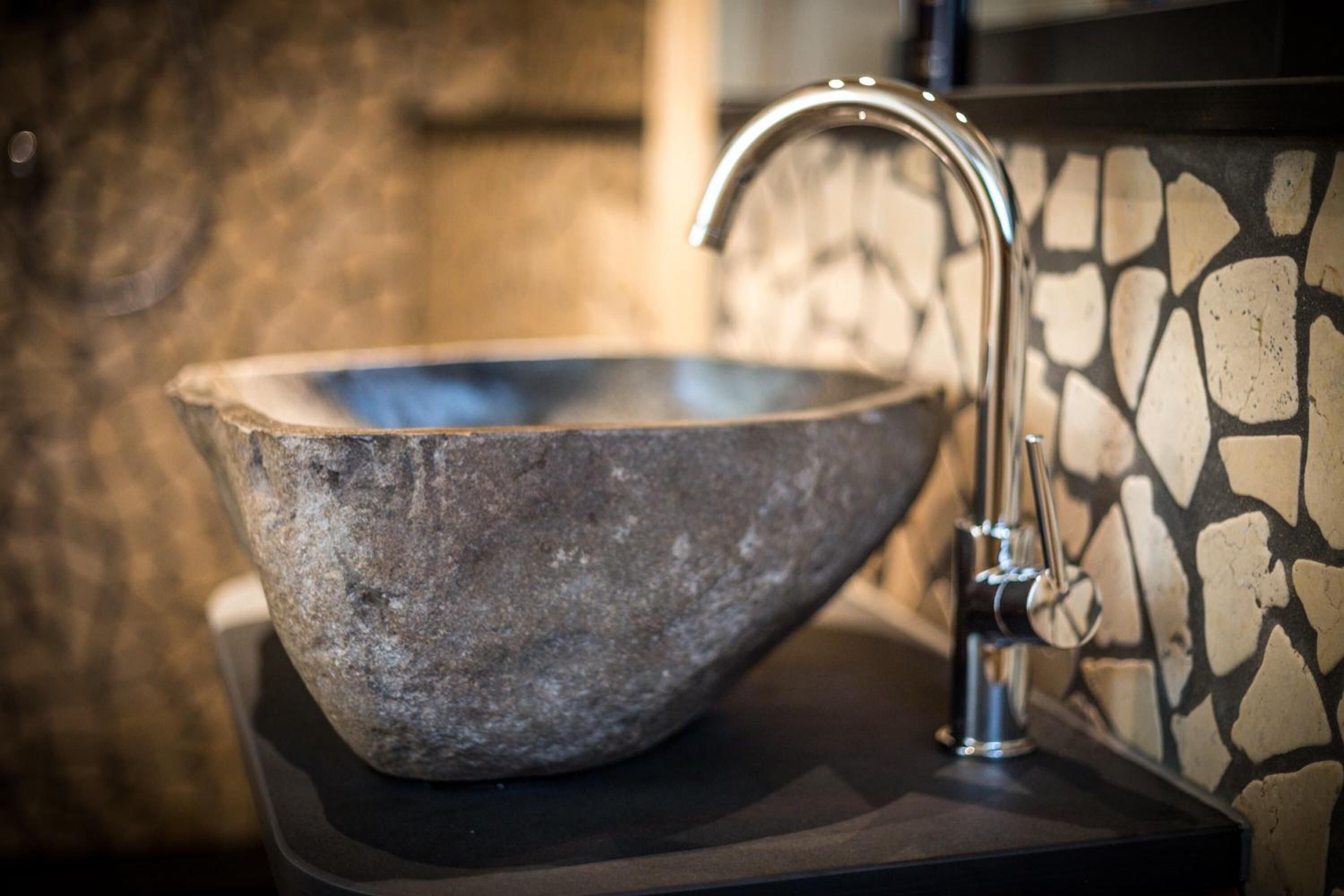 Un lavabo de piedra con un grifo moderno sobre una plataforma negra.