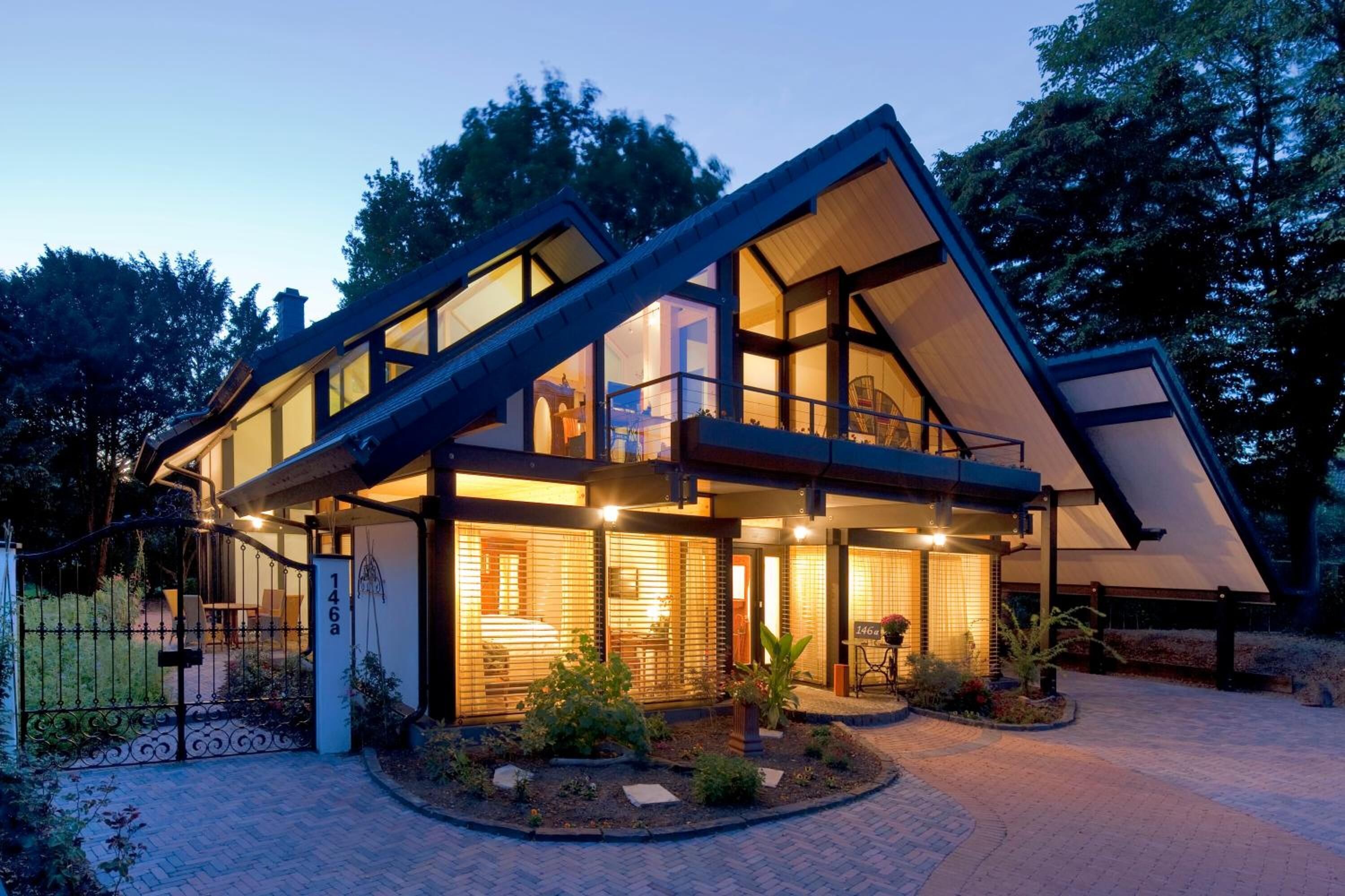 Ein modernes Haus mit Satteldach, großen Fenstern und einer gut beleuchteten Eingangsparte.