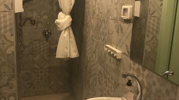 Een badkamer met een douche, een wastafel en een spiegel.