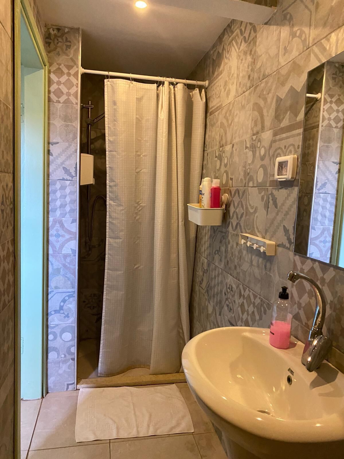A bathroom with a shower, a sink, and a mirror.