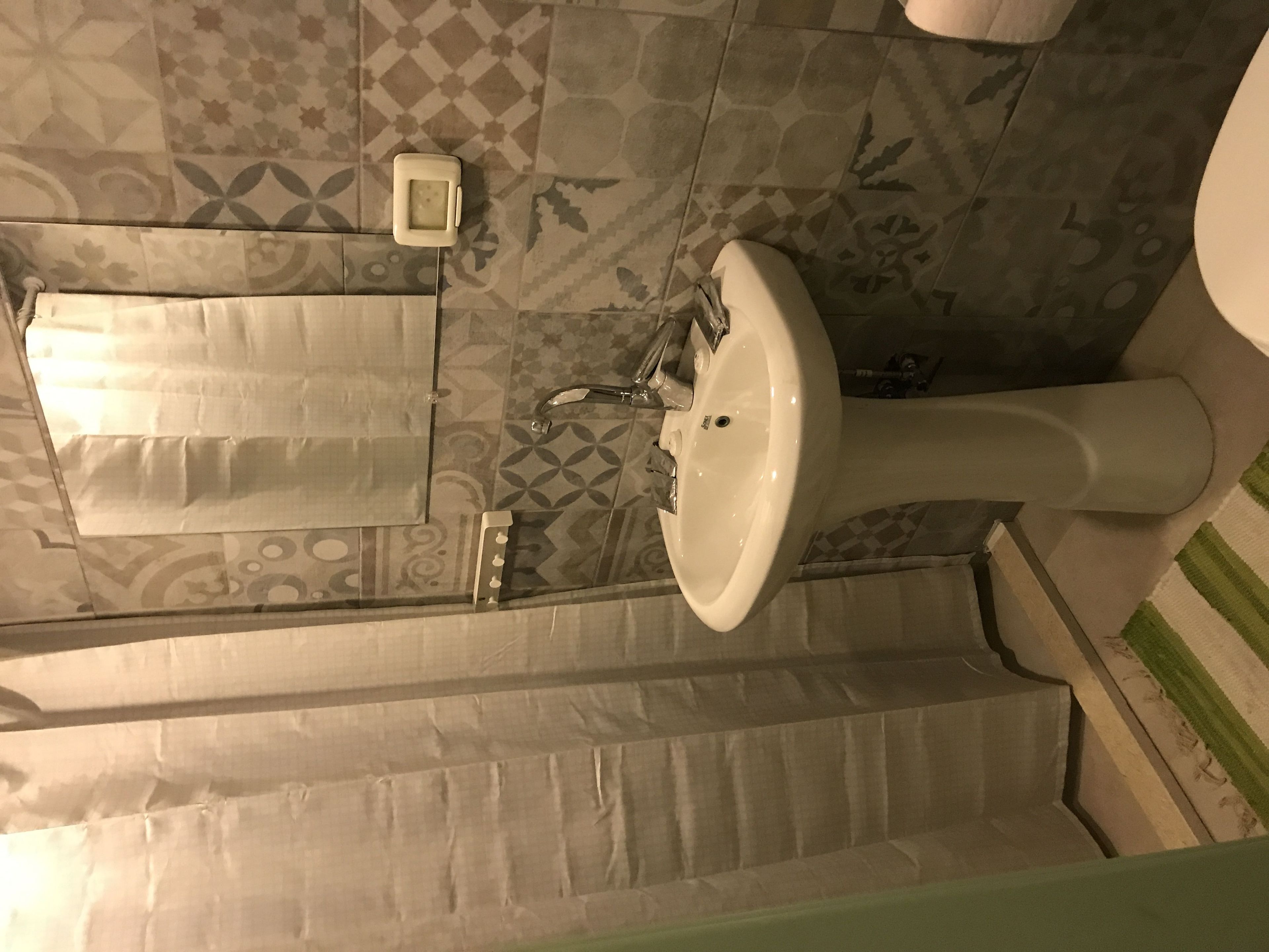A bathroom with a white sink, a towel rack, and patterned floor tiles.