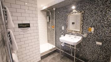 Une salle de bain moderne avec une douche, un lavabo et un miroir. Un panneau est affiché sur le mur, indiquant qu’il est interdit de jeter les articles d’hygiène féminine dans les toilettes.