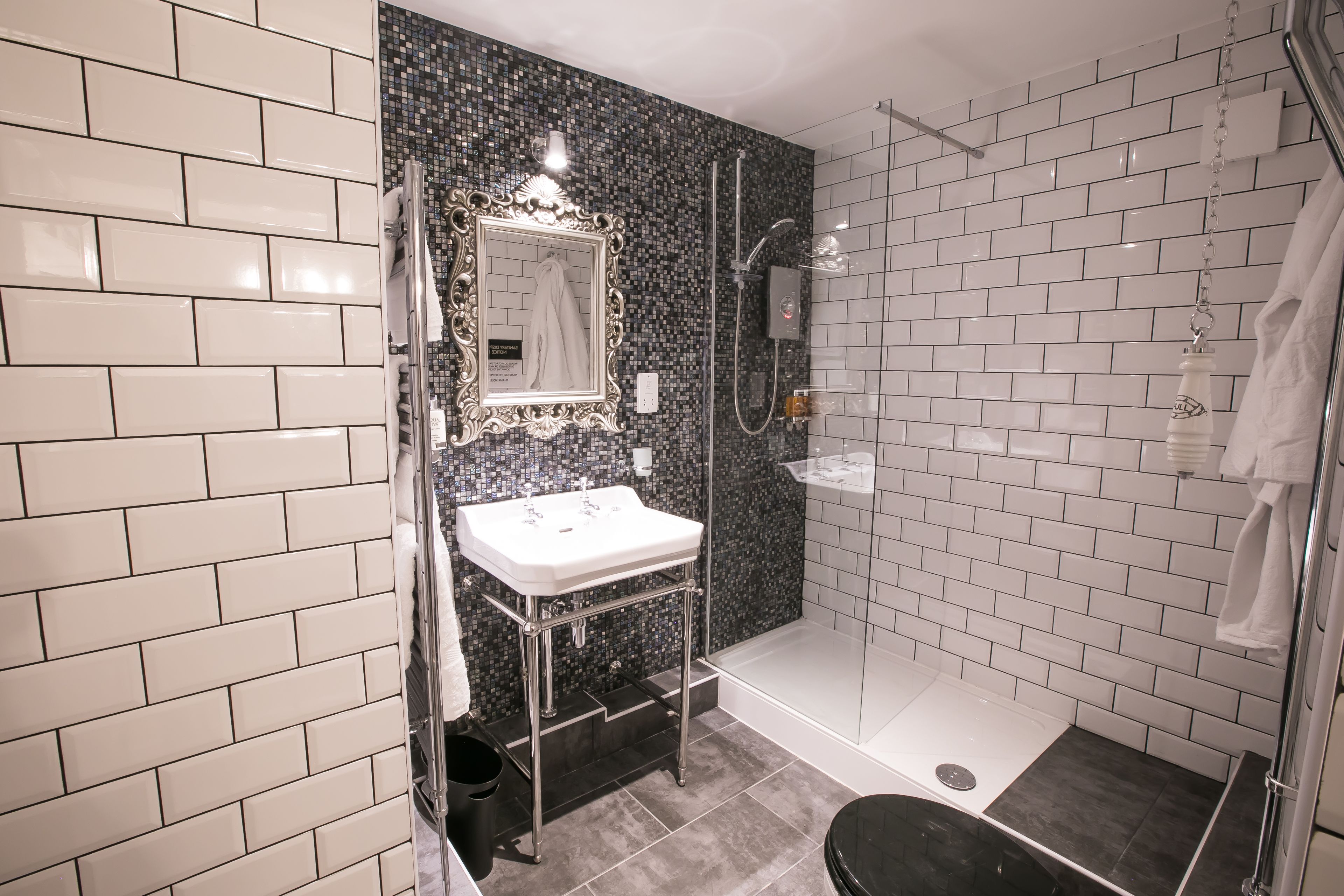 A bathroom with a white sink, a mirror, a shower, and a toilet.