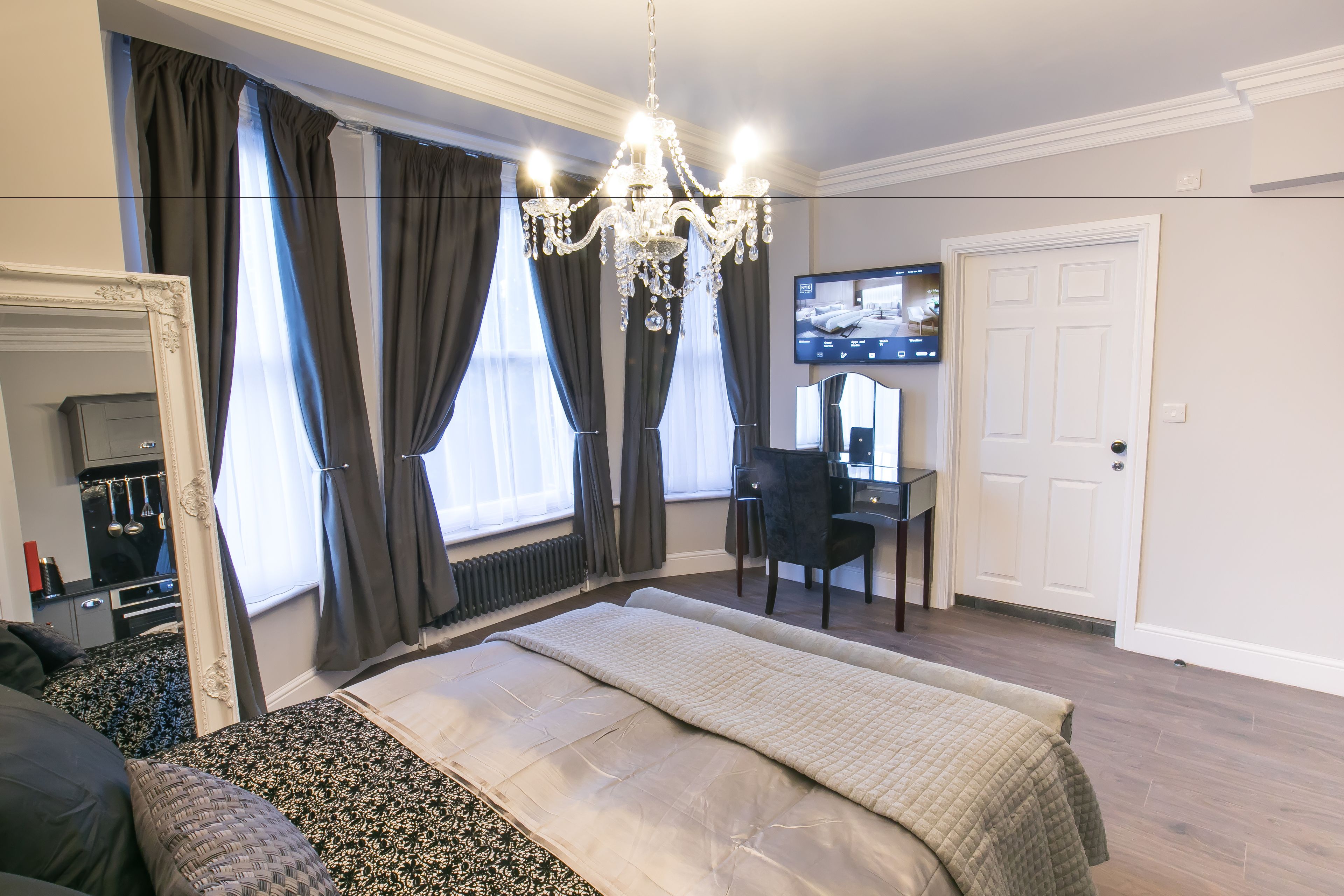 Ein Schlafzimmer mit einem großen Bett, einem Schreibtisch und einem Fernseher.