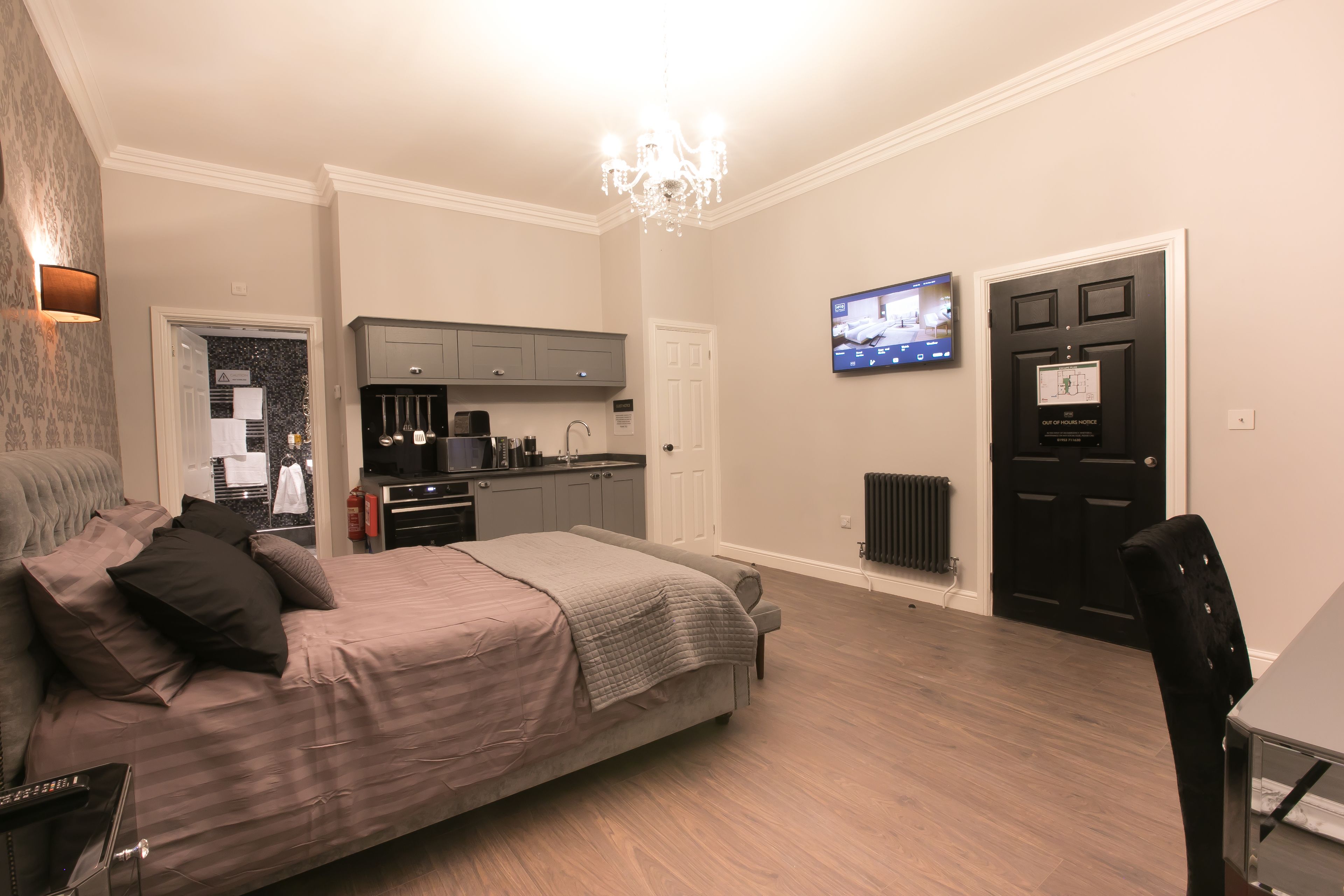 Un dormitorio moderno con una cama grande, un escritorio y una kitchenette.