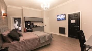 Un dormitorio moderno con una cama grande, un escritorio y una kitchenette.