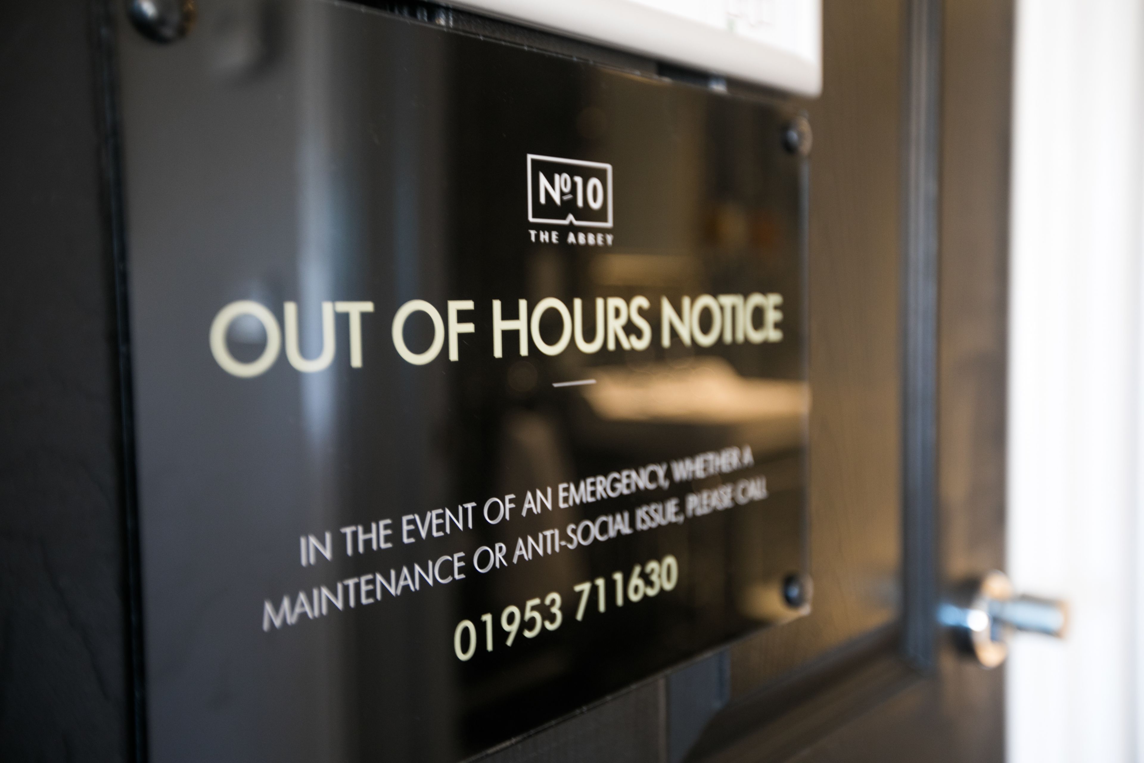 A black sign with white text stating "OUT OF HOURS NOTICE" and a phone number.