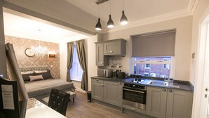 A modern kitchen with grey cabinets, a built-in oven, and a window with a view of the city. - Number 10 The Abbey (Wymondham)
