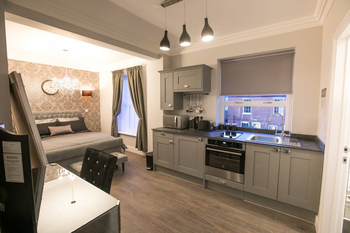 A modern kitchen with grey cabinets, a built-in oven, and a window with a view of the city.