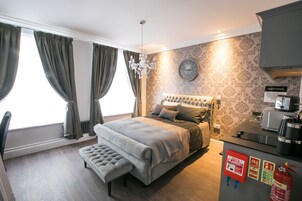 Un dormitorio con una cama grande, un banco, una araña, un reloj y un cartel de seguridad contra incendios.