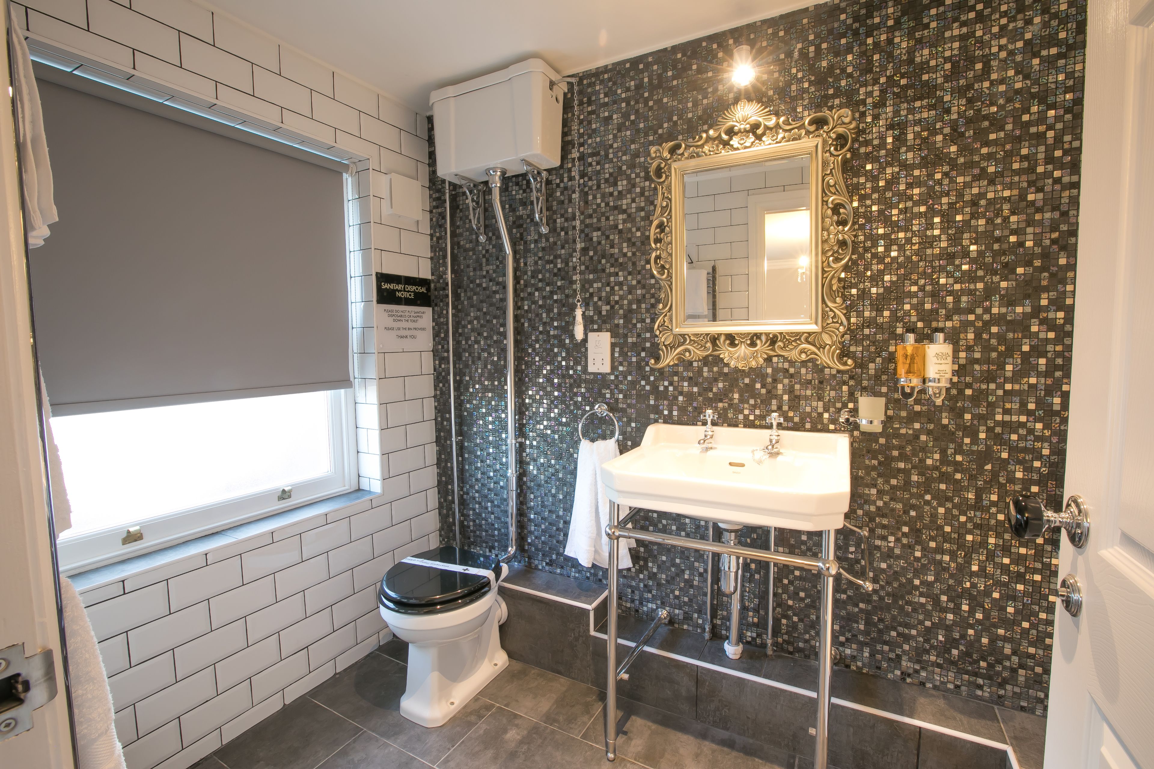 Een badkamer met een toilet, wastafel, spiegel en douche.