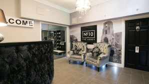 A reception area with a 'WELCOME' sign, a 'No.10 The Abbey' mural, two armchairs, and a black door with the number 10. - Number 10 The Abbey (Wymondham)