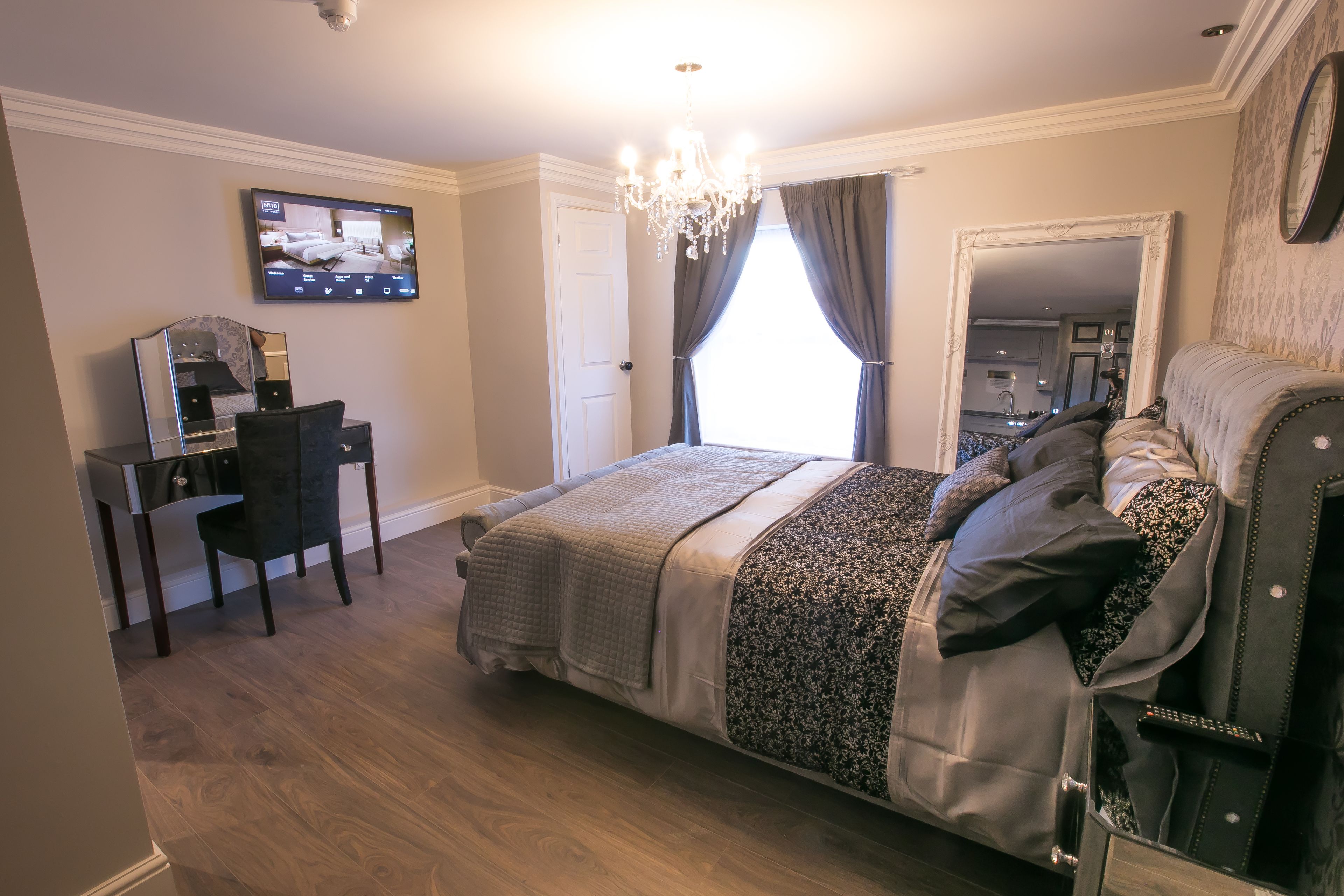 Un dormitorio con cama, escritorio, silla, televisor y candelabro.