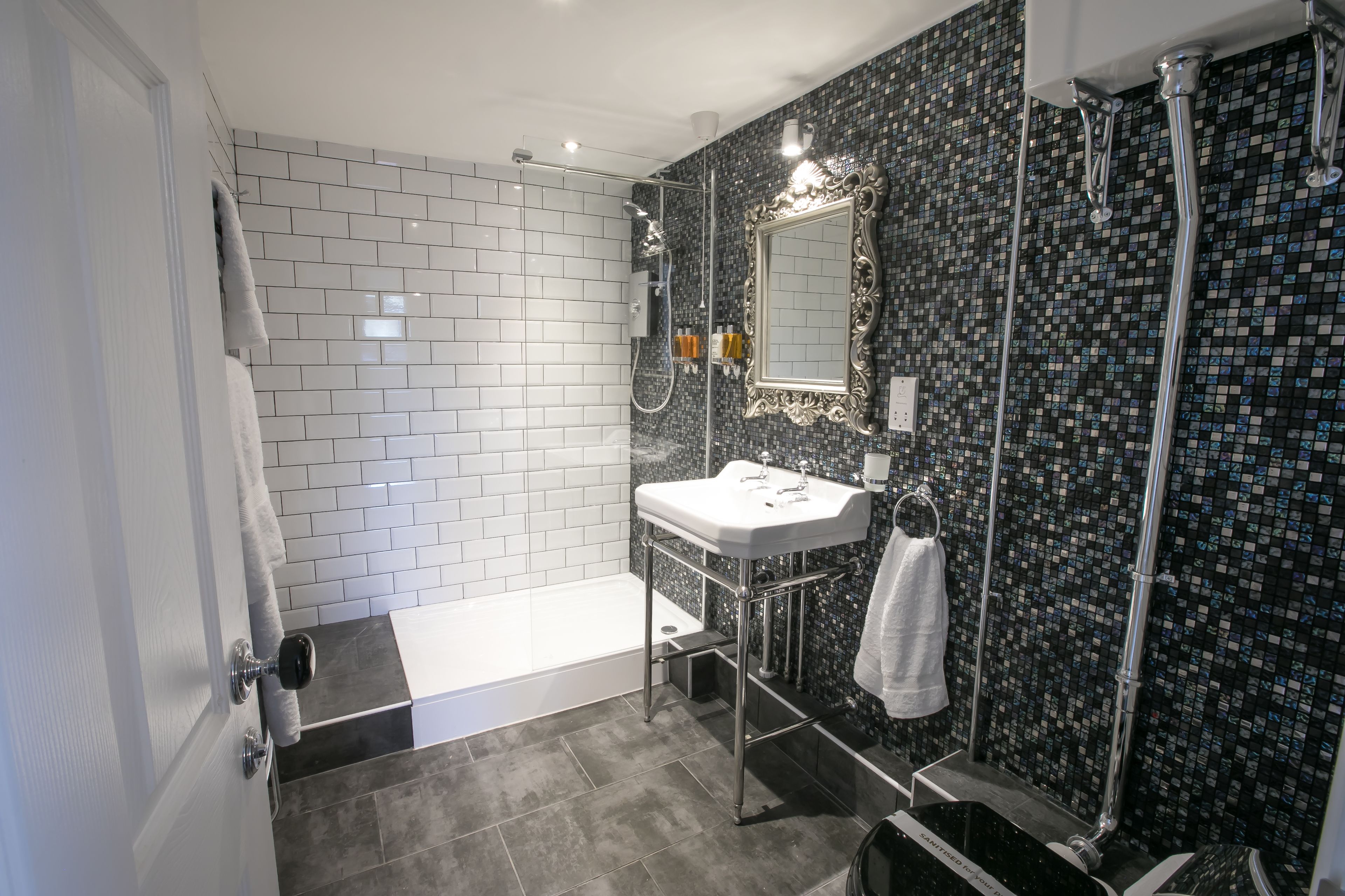 A modern bathroom with a white sink, a large mirror, and a shower area.
