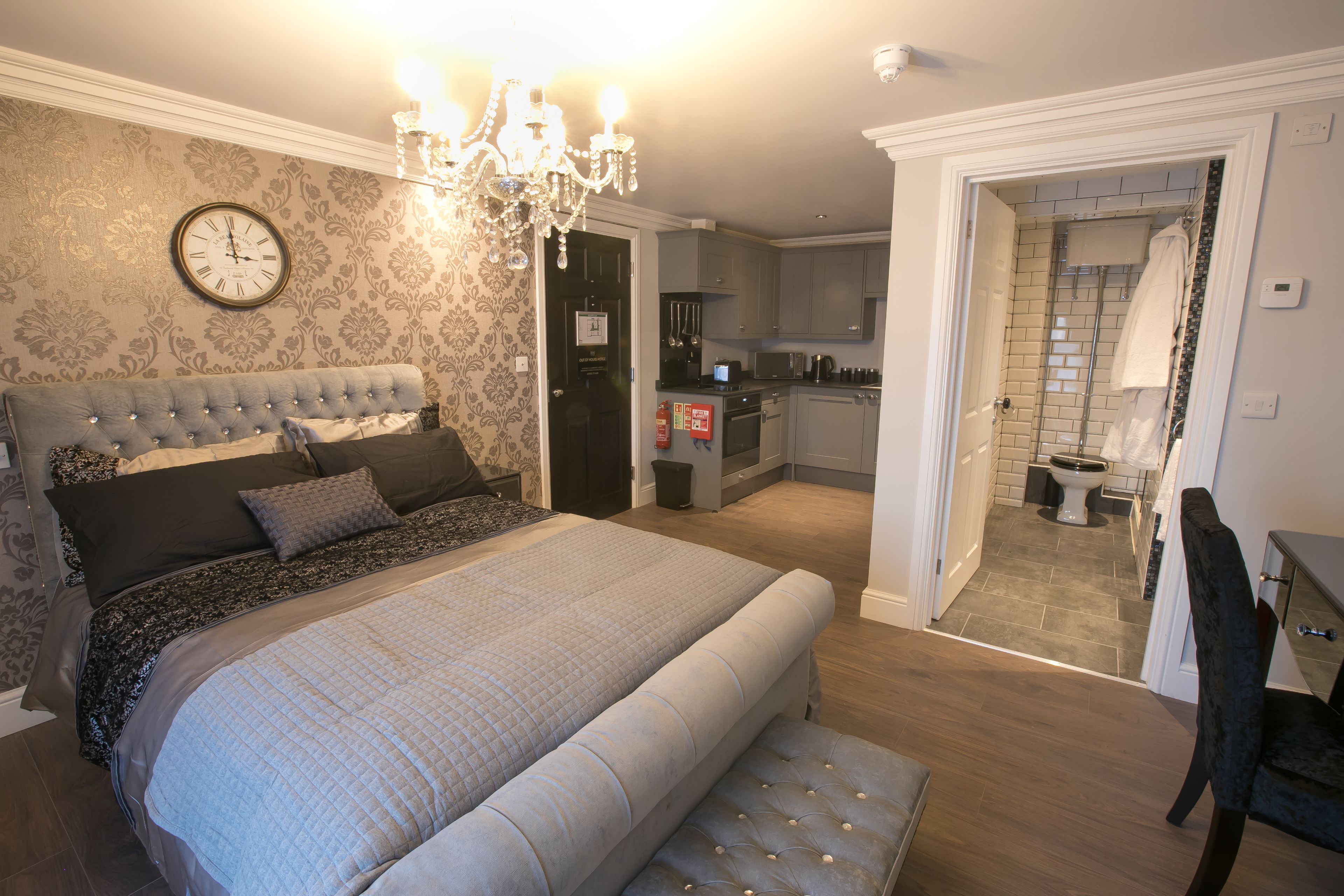 A bedroom with a large bed, a chandelier, and a clock on the wall.