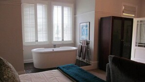 Ein Badezimmer mit einer Badewanne, einem großen Spiegel und einem dunklen Holzschrank.