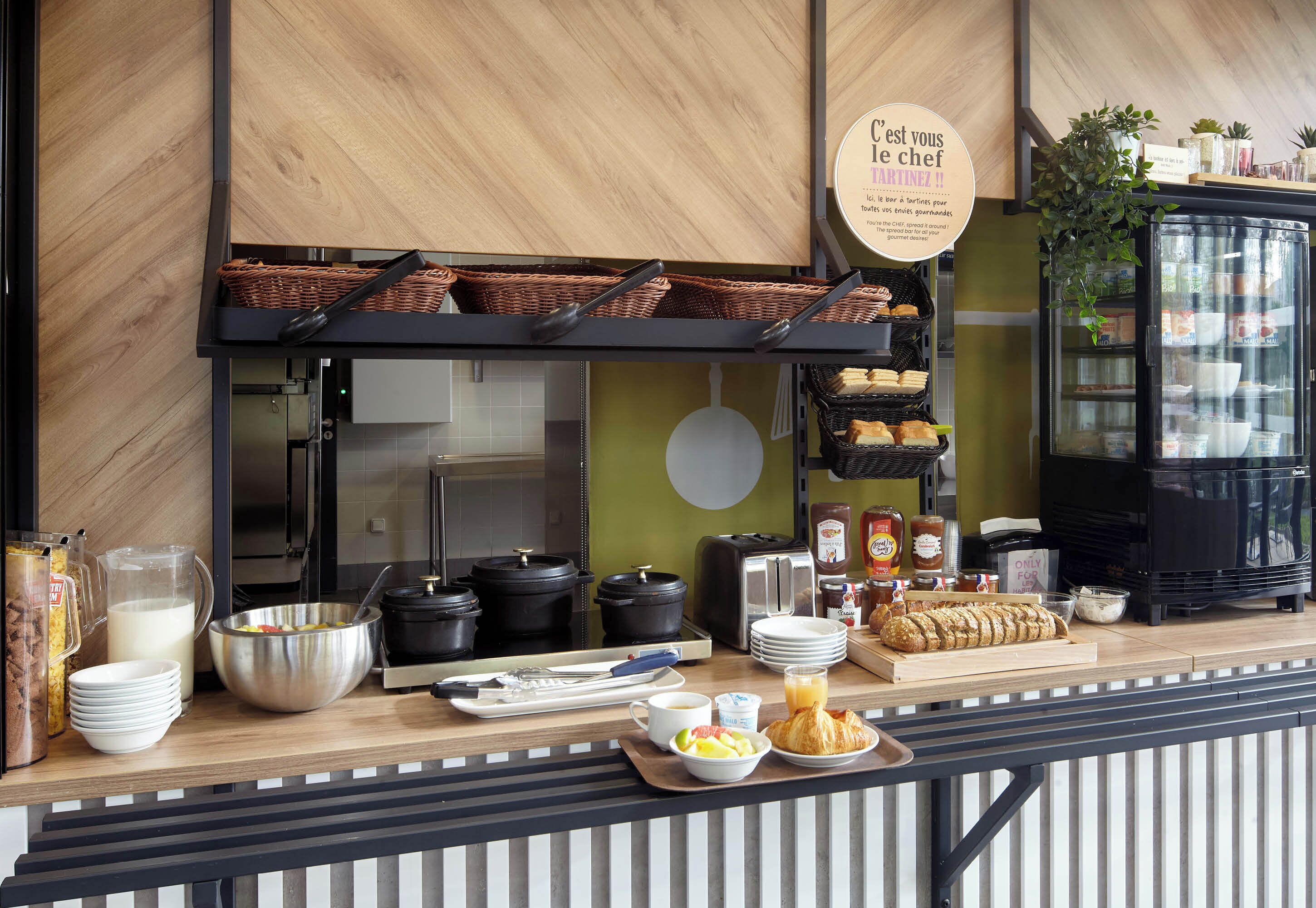 Un buffet de petit-déjeuner proposant divers aliments, du matériel de cuisine et un panneau indiquant qu’il s’agit de l’espace réservé au chef.