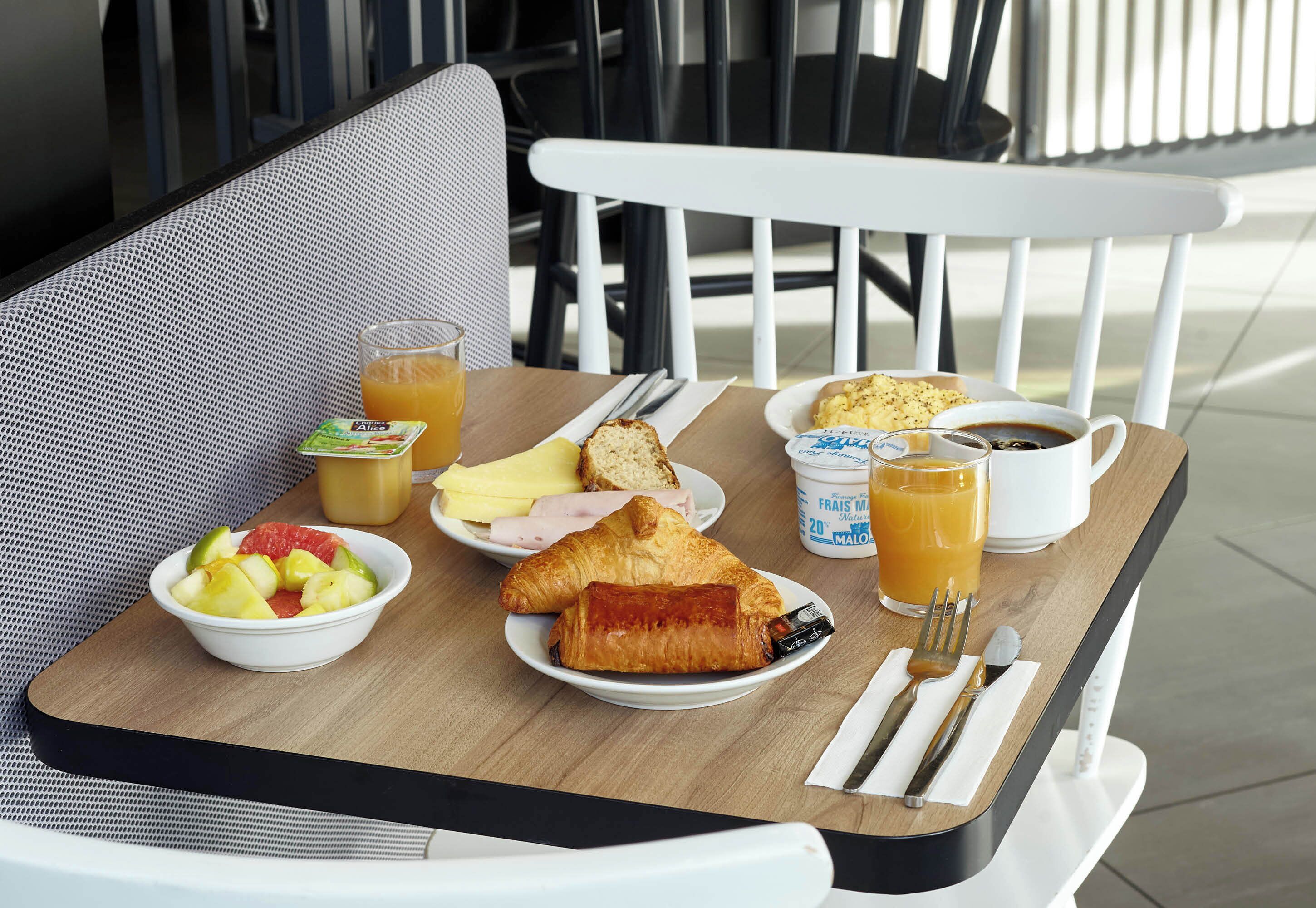 A breakfast table with croissants, fruit, and a cup of coffee.