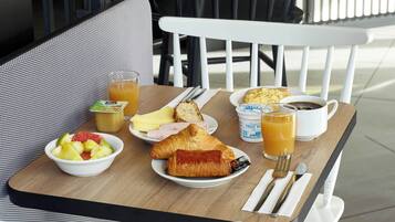 A breakfast table with croissants, fruit, and a cup of coffee.