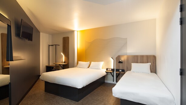 A hotel room with a large bed, bedside tables, a flat-screen TV, and a unique wall art piece. - B&B HOTEL NANTERRE Rueil Malmaison (Nanterre)