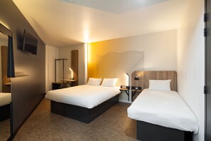 Una habitación de hotel con una cama grande, mesitas de noche, un televisor de pantalla plana y una obra de arte original en la pared.