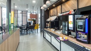 A modern cafe with a counter, coffee machines, and seating area. - B&B HOTEL NANTERRE Rueil Malmaison (Nanterre)