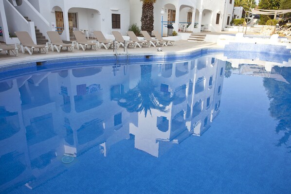 Una piscina al aire libre de temporada, sombrillas, tumbonas