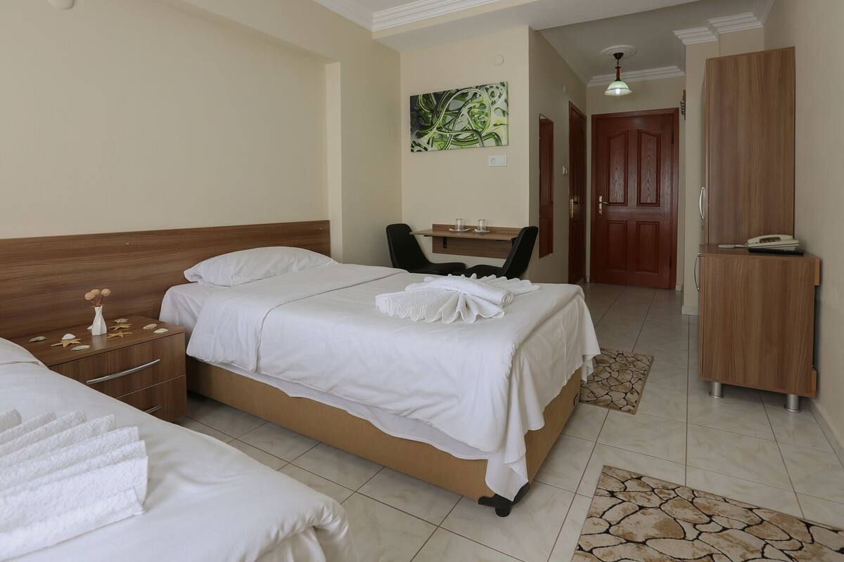 A hotel room with a bed, a desk, a chair, a wardrobe, and a bathroom.