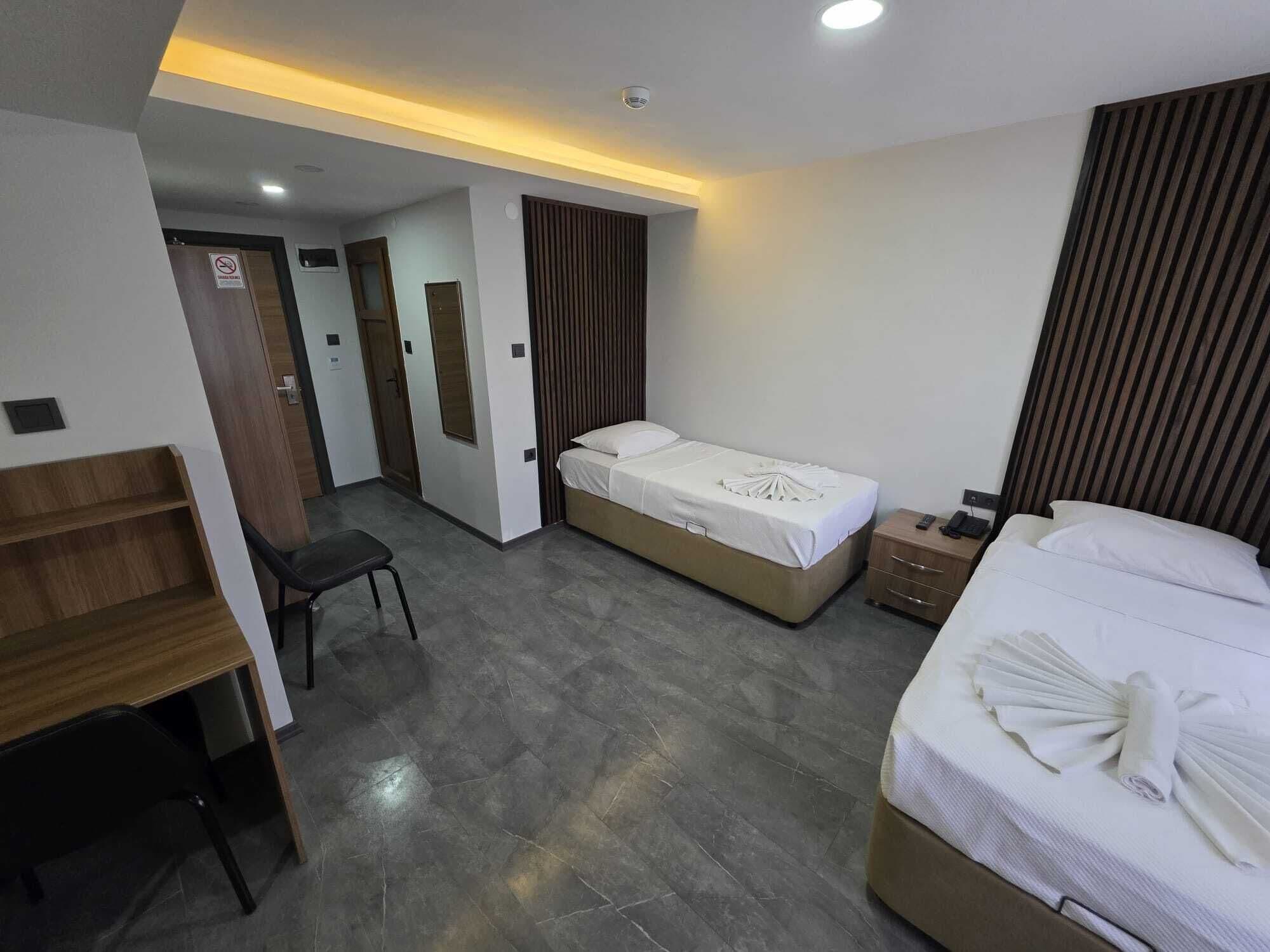 A hotel room with two beds, a desk, and a chair.