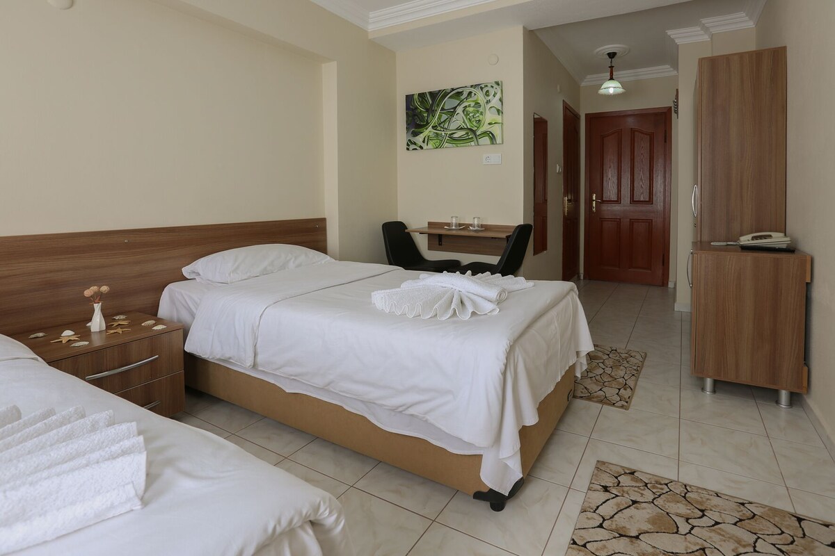 A hotel room with a bed, a desk, a chair, a wardrobe, and a bathroom.