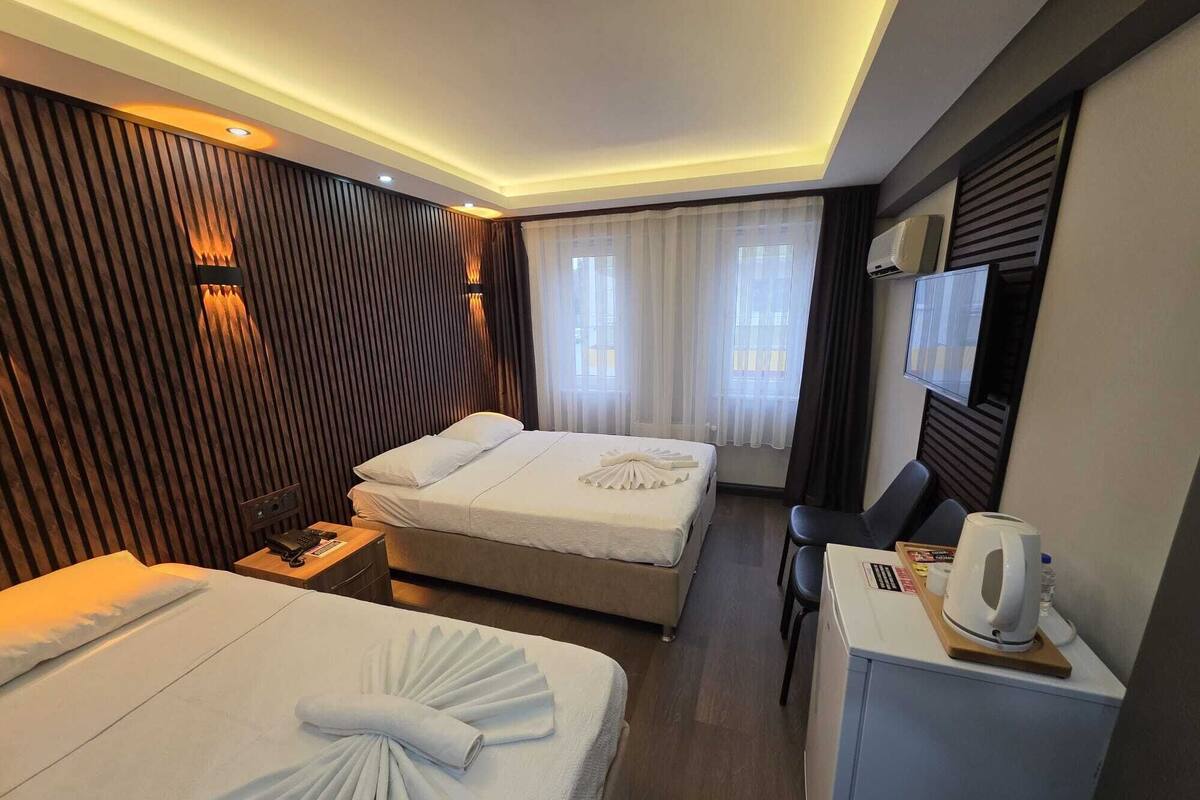 A hotel room with two beds, a desk, a chair, a TV, and a minibar.