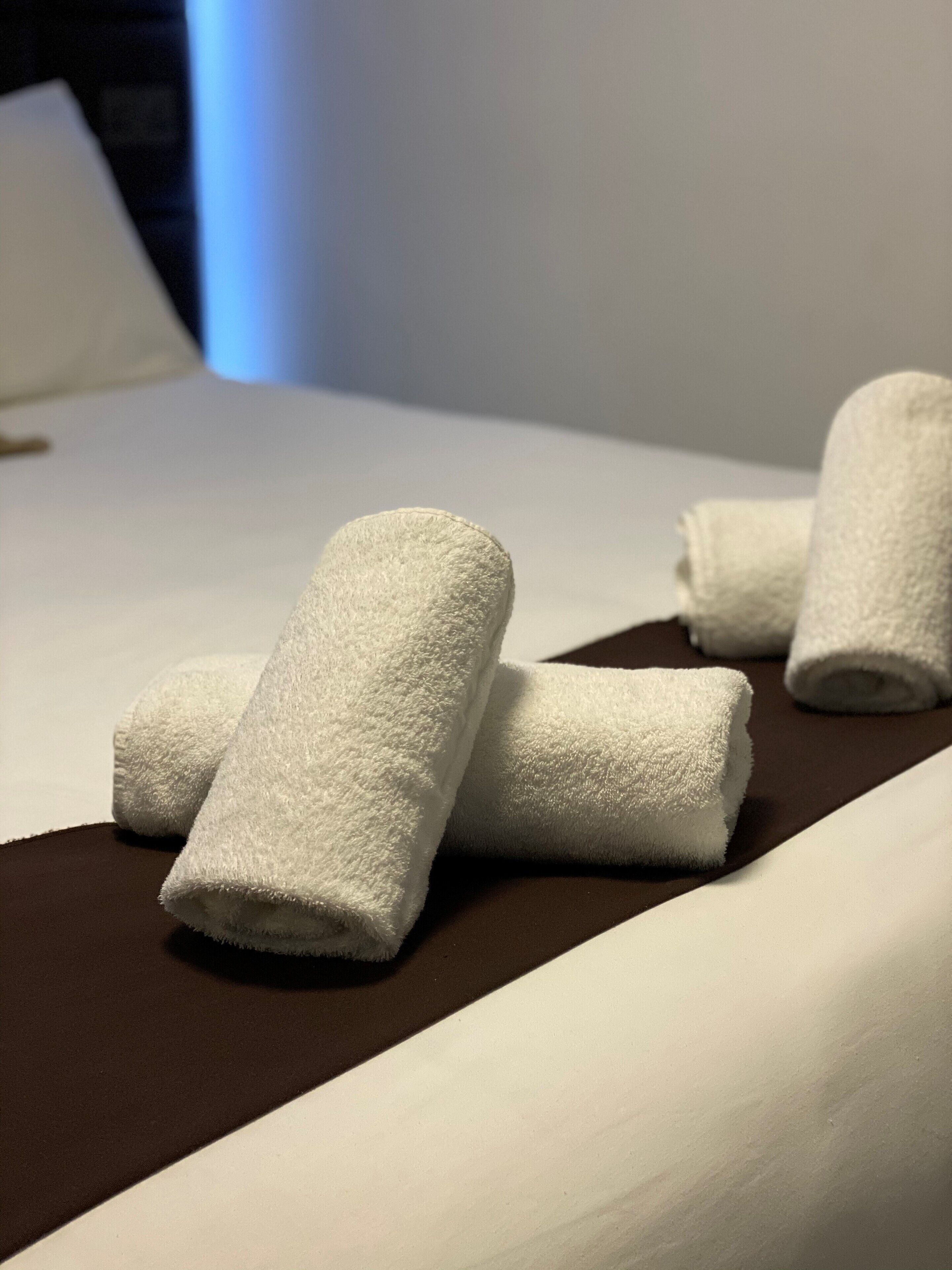 Un lit bien fait, avec du linge de lit blanc et des serviettes enroulées.