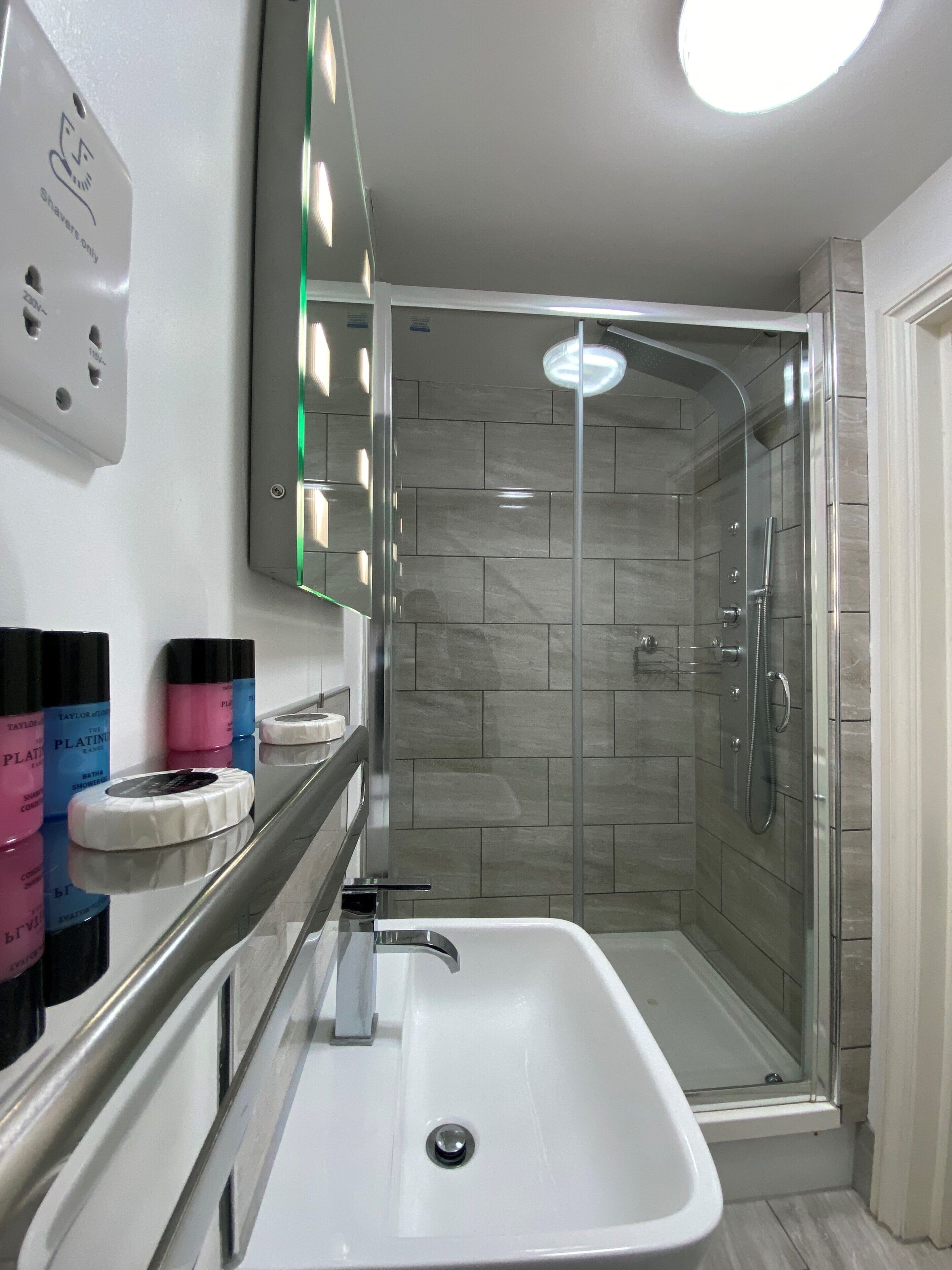 A modern bathroom with a glass-enclosed shower, a white sink, and a mirror above the sink.