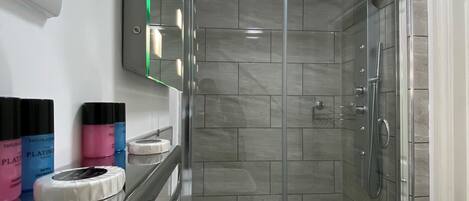 A modern bathroom with a glass-enclosed shower, a white sink, and a mirror above the sink.