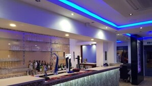 A modern bar area with a counter, shelves with bottles, and a blue-lit ceiling. - The Charles Hotel (Chatham)