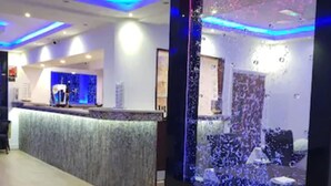 A reception area with a modern design, featuring a reception desk, a large digital screen displaying an abstract image, and ambient blue lighting. - The Charles Hotel (Chatham)