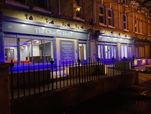 El Hotel Charles, con una zona de recepción, una terraza y un cartel que enumera servicios como servicio de habitaciones las 24 horas, televisión, wifi, desayuno y un salón de recepción.