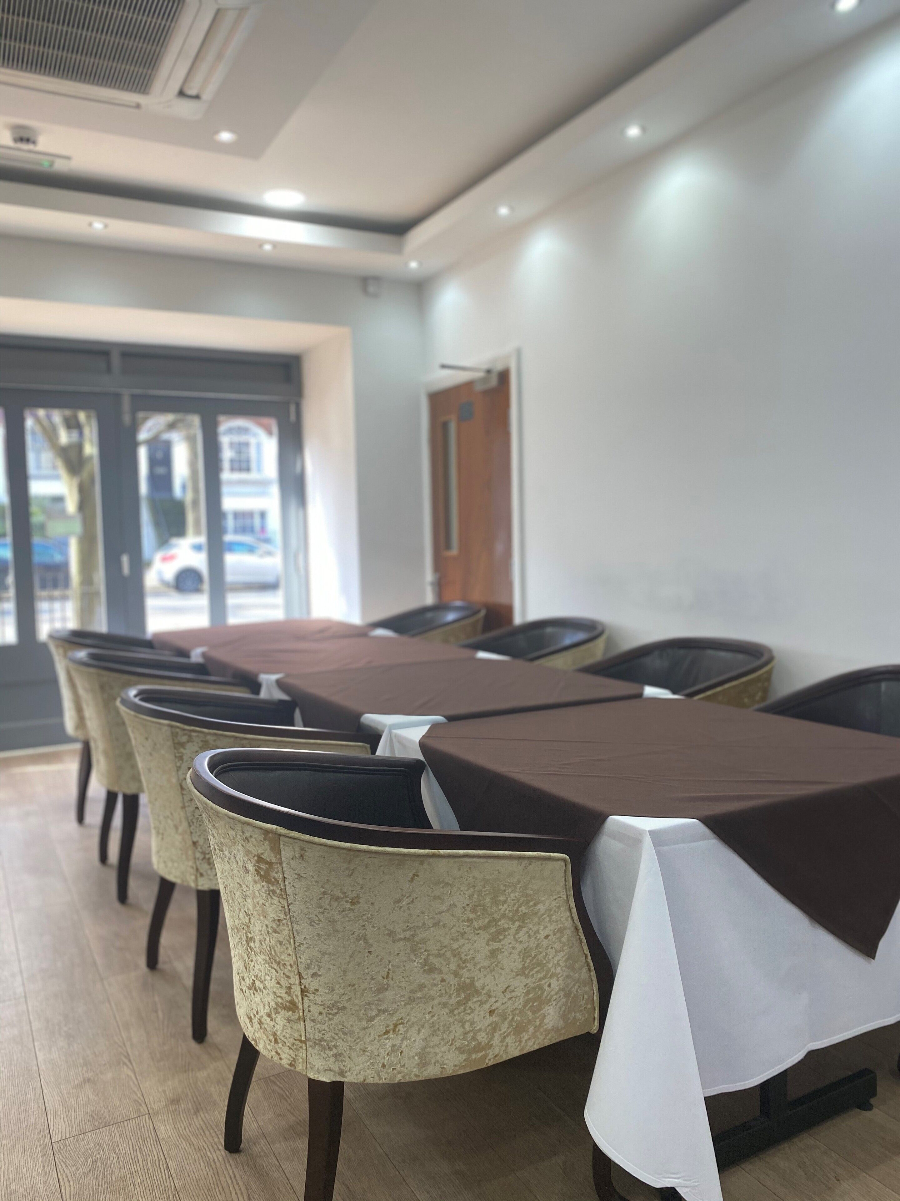 A conference room with a long table and several chairs, a door, and a window with a view of the street.