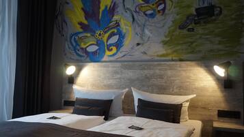 Relax in a stylish retreat with a large bed, wall-mounted lamps, and a vibrant mural.