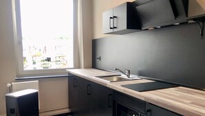 A modern kitchen with a window, built-in oven, and a black refrigerator. - Urban Home Self Check-In Hotel (Hamburg)