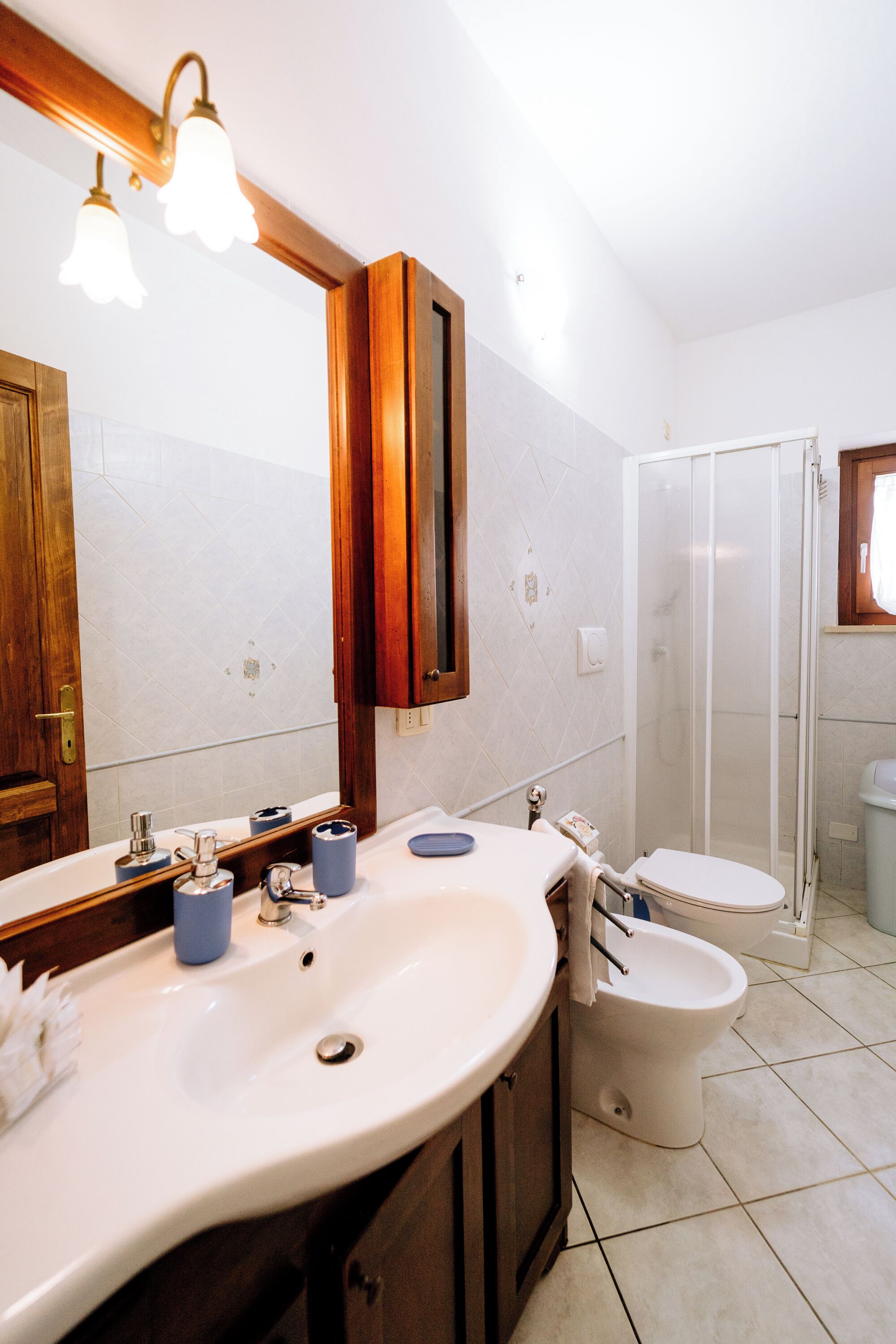 A bathroom with a large mirror, two sinks, a toilet, and a glass-enclosed shower.