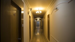 Un couloir d'hôtel avec un lustre, des portes en bois et un plancher ciré.