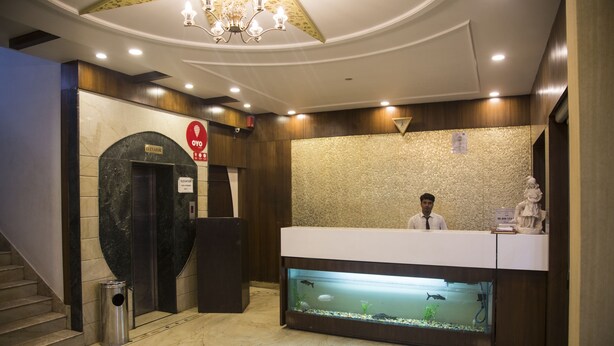 Un espace d’accueil comprenant un comptoir de réception, un bureau d’accueil avec un aquarium, un escalier et un ascenseur.