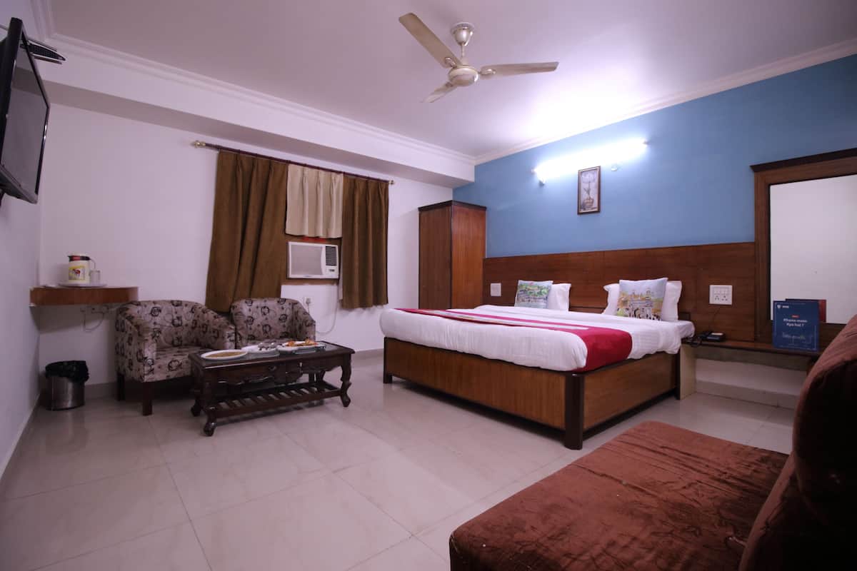 Una habitación de hotel con cama, sofá, mesa de centro, televisor y ventilador de techo.