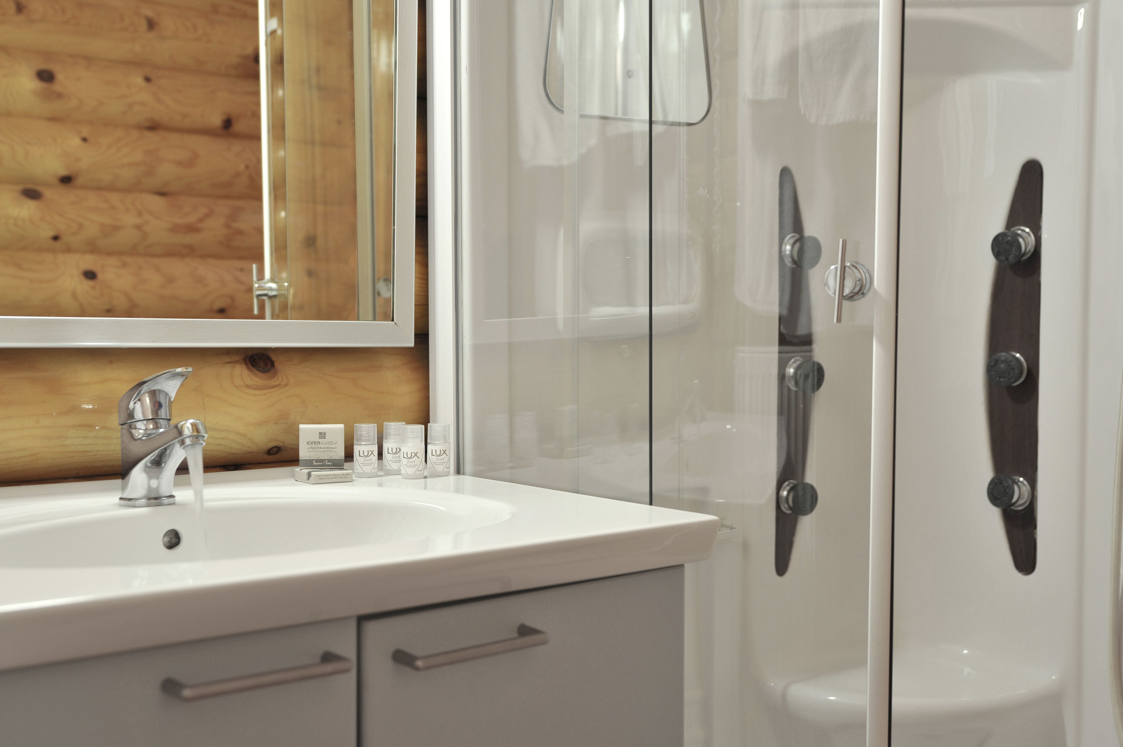 Un baño con un lavamanos blanco, un espejo y cabina de ducha de vidrio.