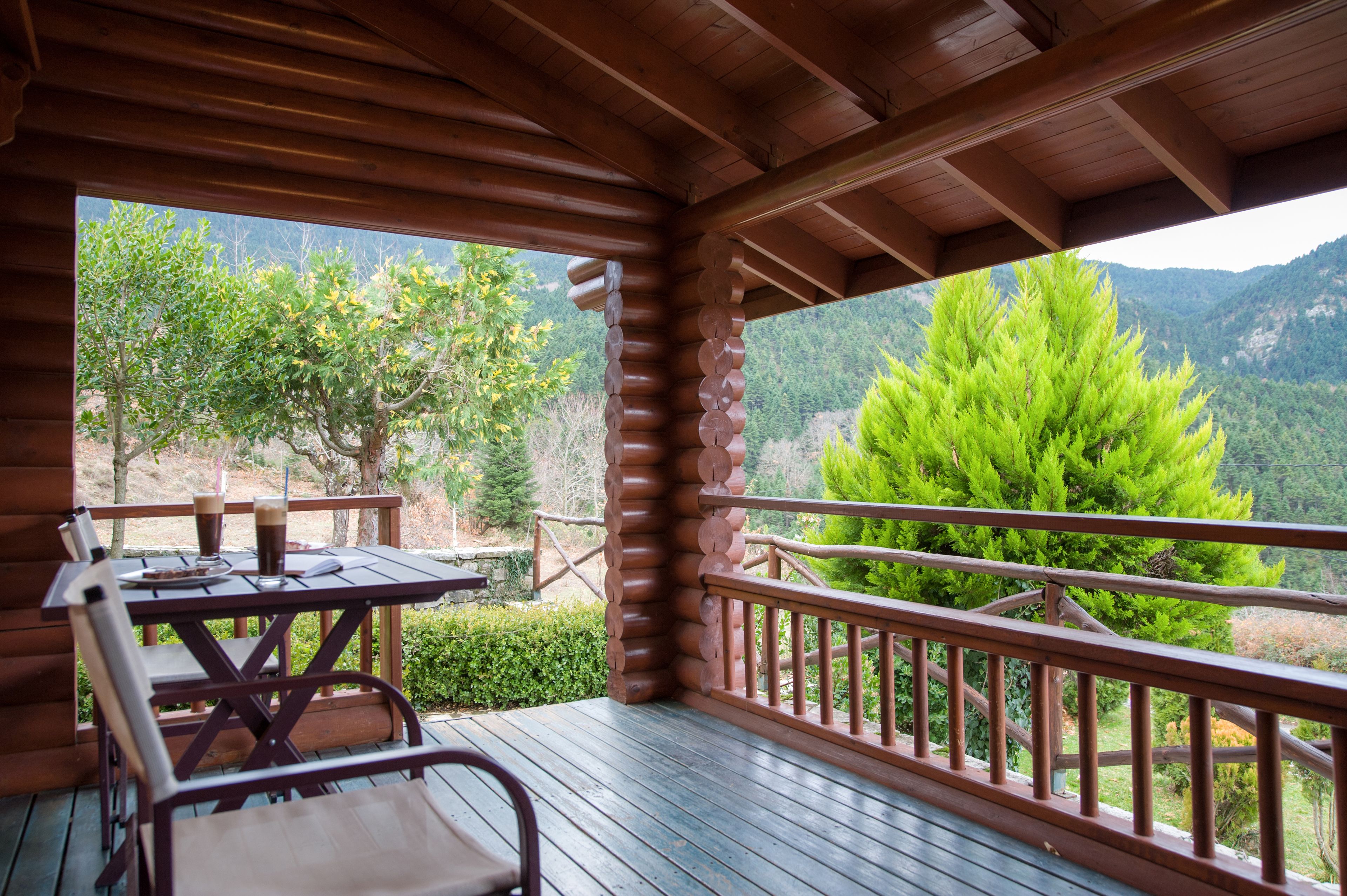 Una terraza de madera con una mesa y sillas, con vista a un paisaje montañoso.