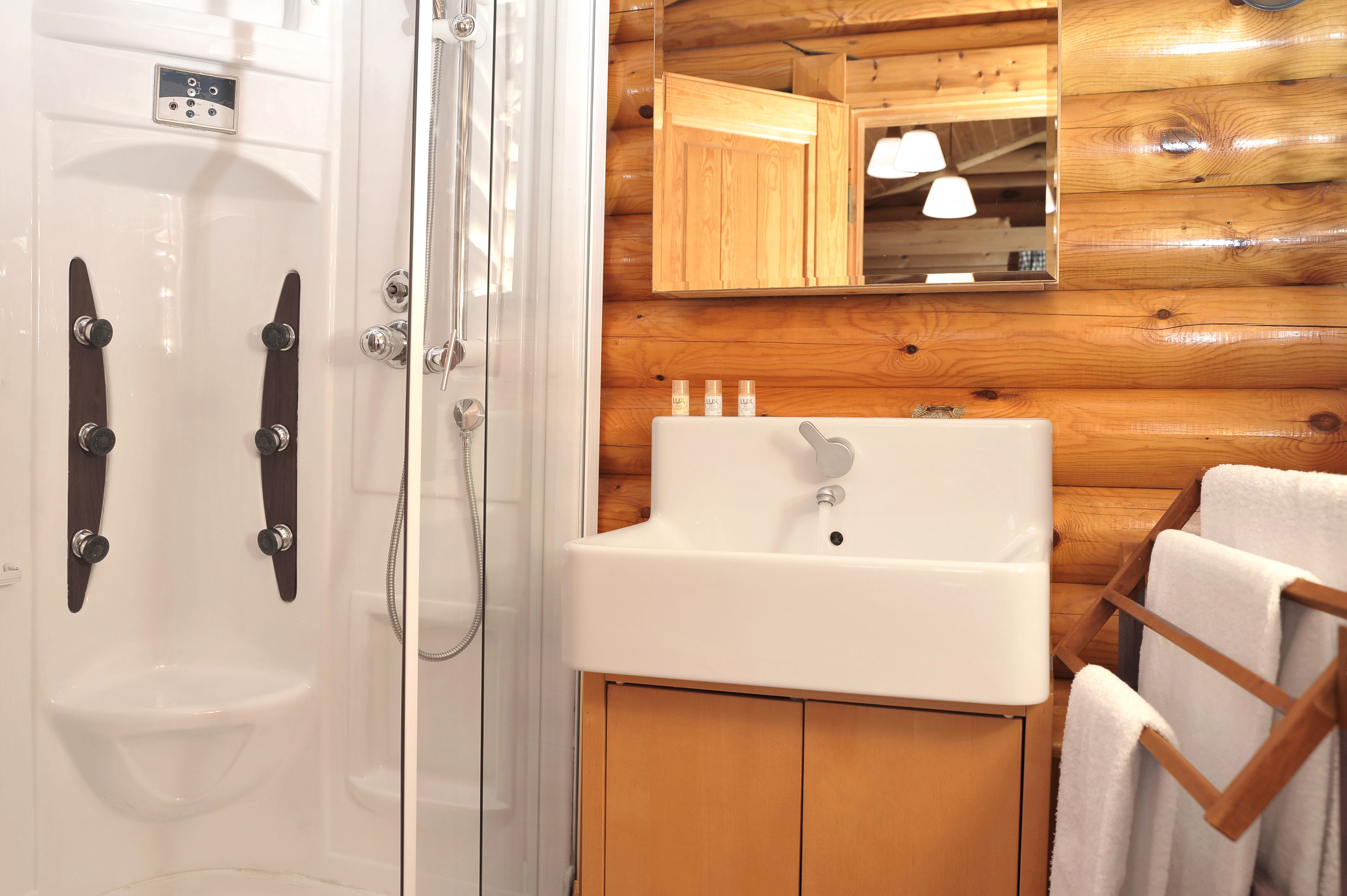 A bathroom with a shower, a sink, and wooden walls.